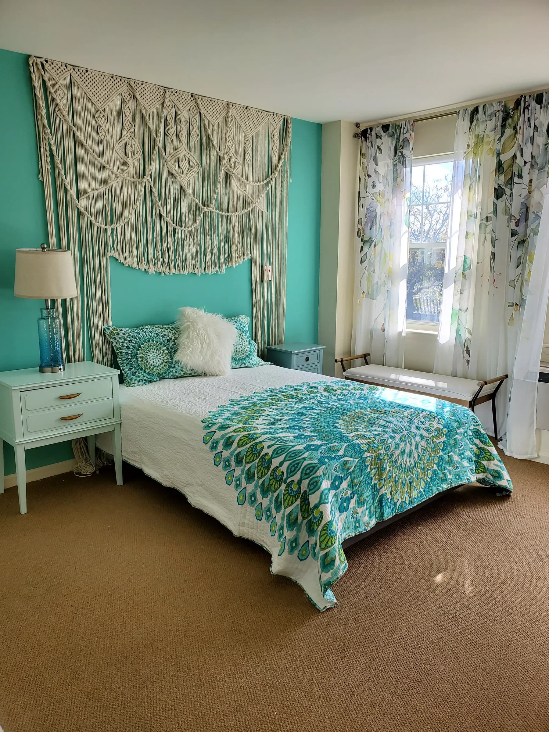 Turquoise bedroom with woven wall hanging, patterned bedding, and airy window treatments — designed by Renata Glaz